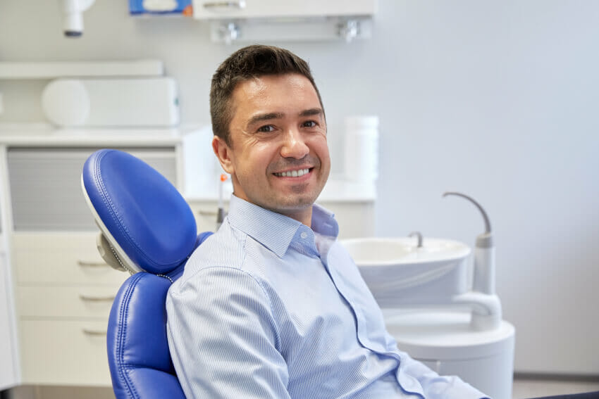 Man smiling in dental chair awaiting a dental extraction