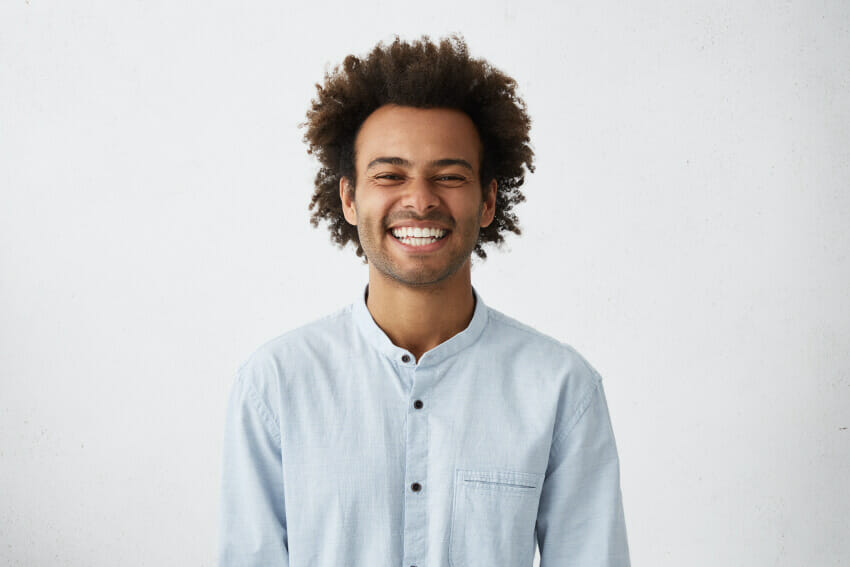 Man with curly brown hair, button up shirt smiling